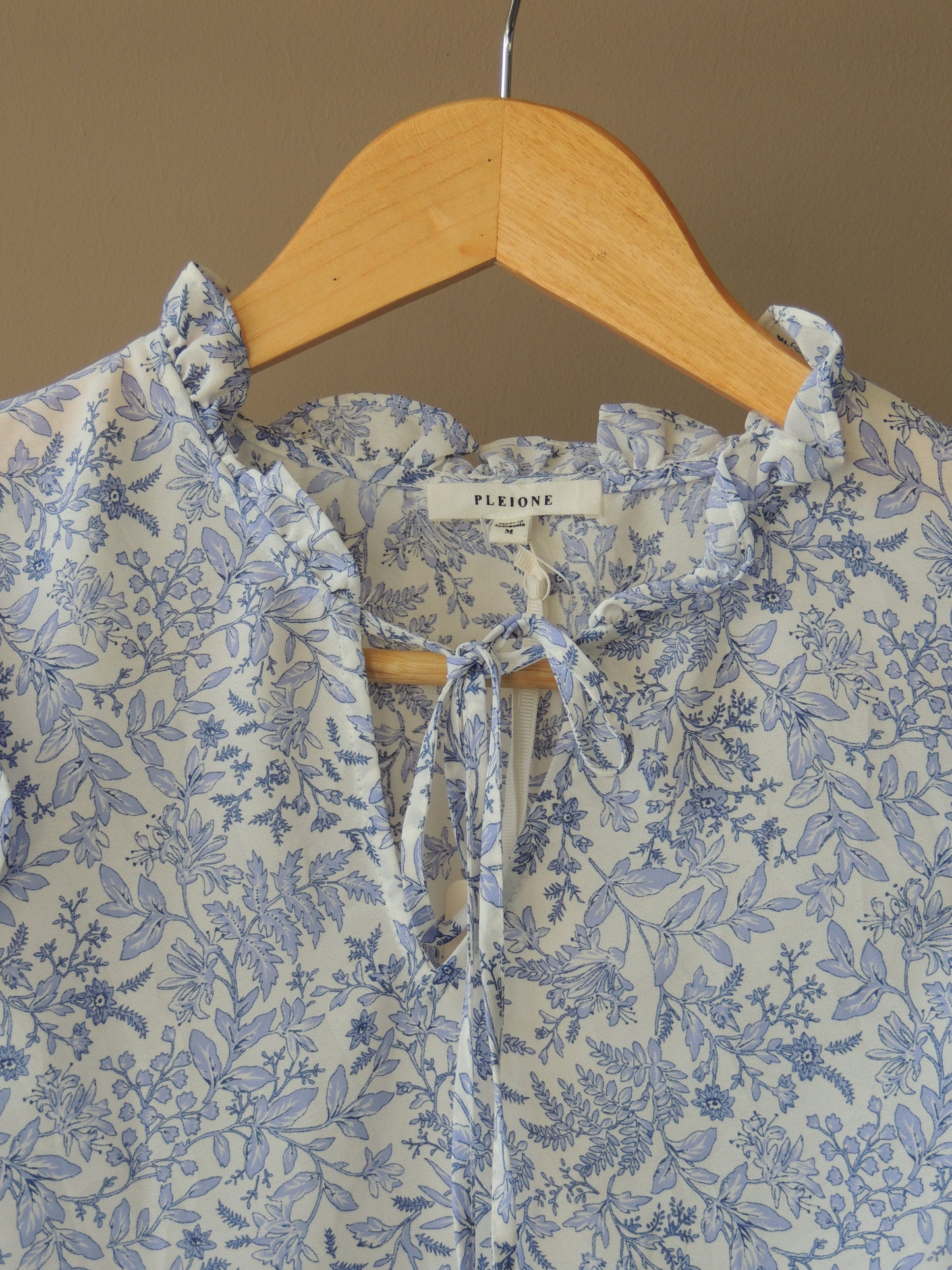 Blusa Pleione, con motivo floral en celeste, bolados y lazo, talle M, con etiqiueta